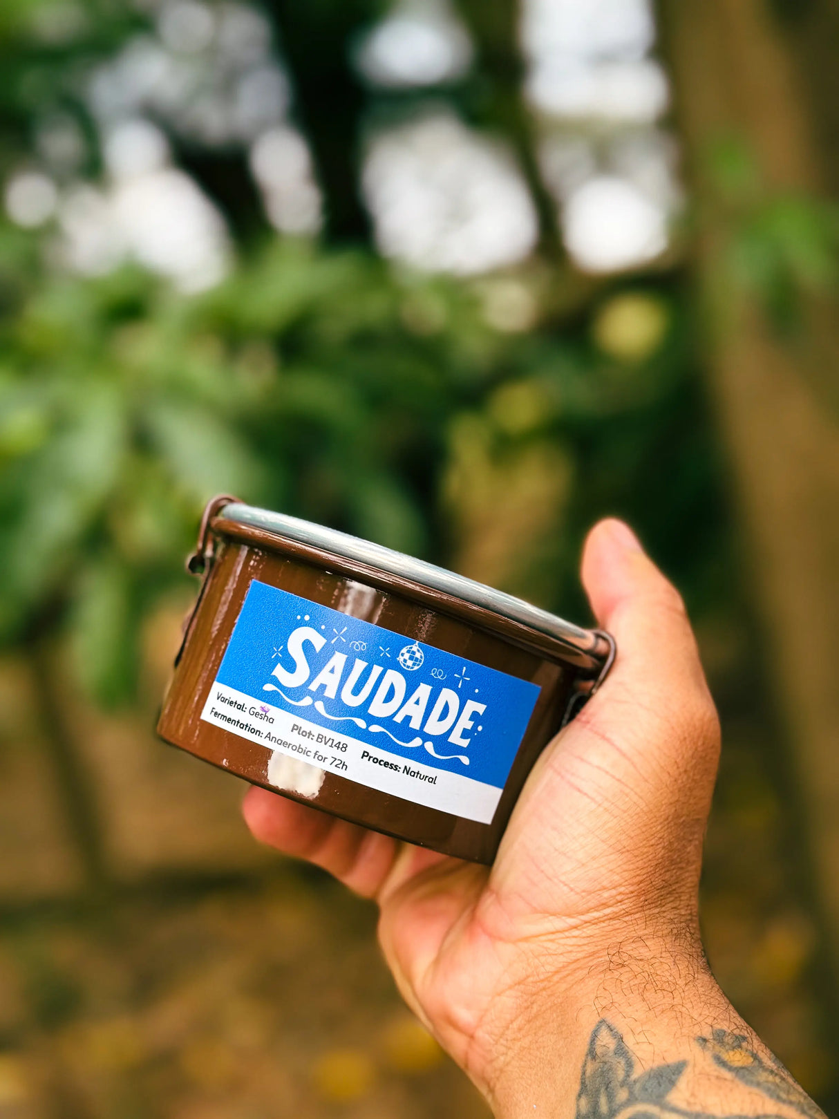 Hand holding a container of 'Saudade' from the Daterra Masterpieces coffee auction