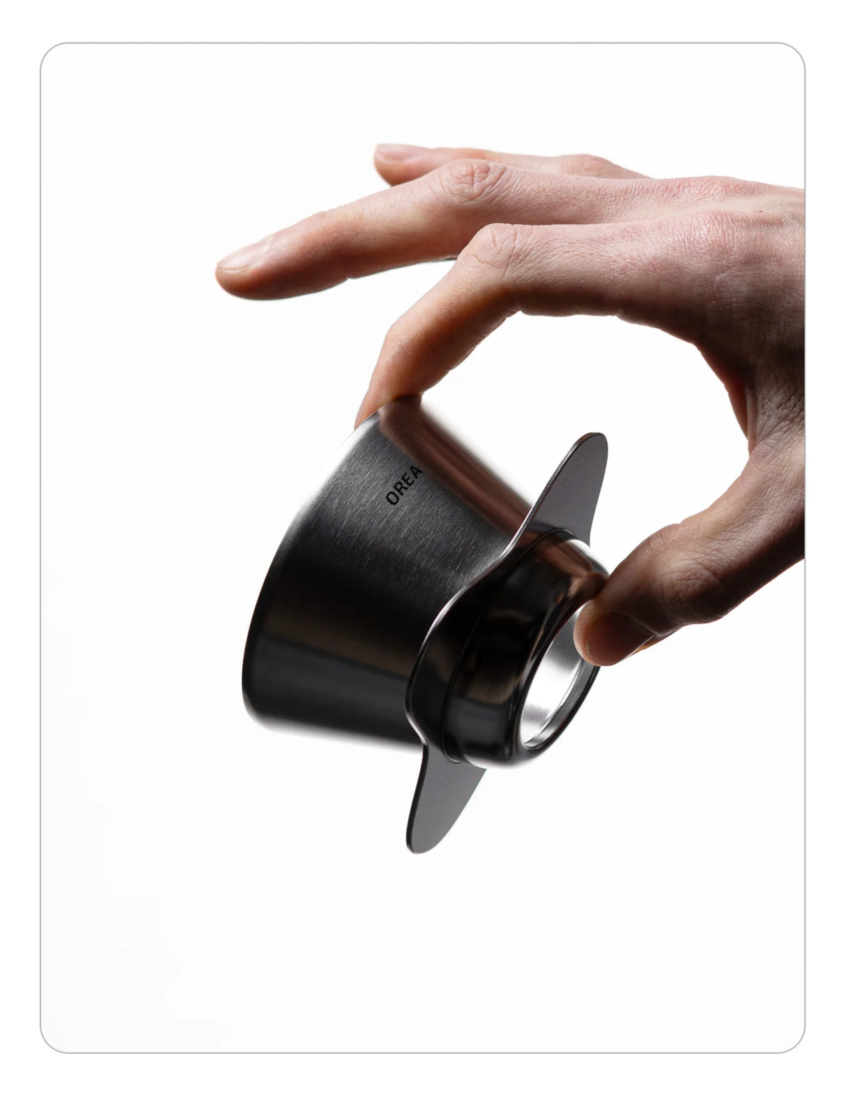 Hand holding an OREA 01 raw steel coffee dripper on a white background