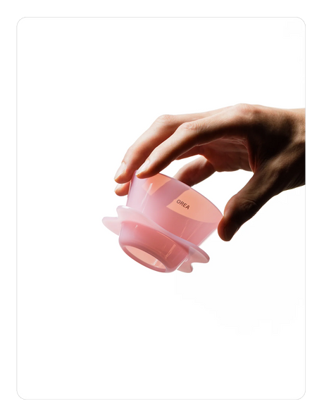 Hand holding a Creamy pink OREA 01 brewer on a white background